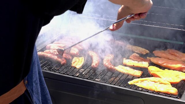 Man grilling meat on an outdoor barbecue. Leisure time with friends