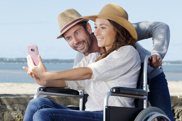couple by the beach in wheelchair taking selfie