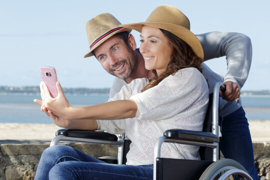couple by the beach in wheelchair taking selfie