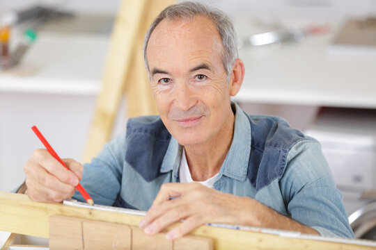 portrait of senior man measuring wood - Powered by Adobe