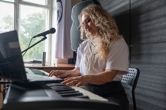 Caucasian woman singing into microphone and playing synthesizer.