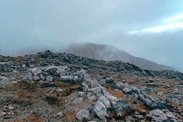 Oxidized volcanic rock landscape disappearing into the fog near the volcano summit