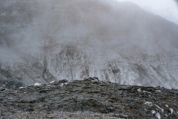 Close-up of the desolate, mist-shrouded, mineral-stained Poás Volcano crater wall, Costa Rica.