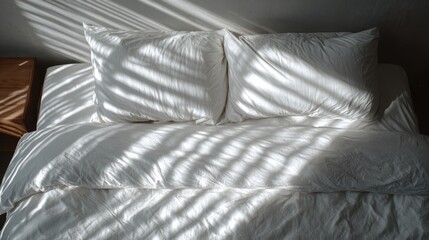 Morning sunlight casting shadows on cozy bed with white pillows and duvet