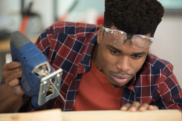 young man cuts wood products using electric jigsaws