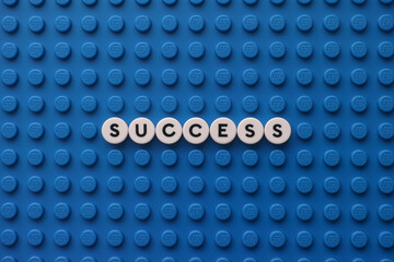 Naklejka premium Tambov, Russian Federation - November 24, 2025 The word Success on a blue Lego baseplate. The scene is made out of Lego dots.