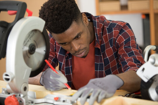 young carpenter with pencil measuring and marking wooden plank - Powered by Adobe