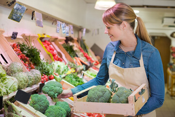 female staff holding broccoli in organic section