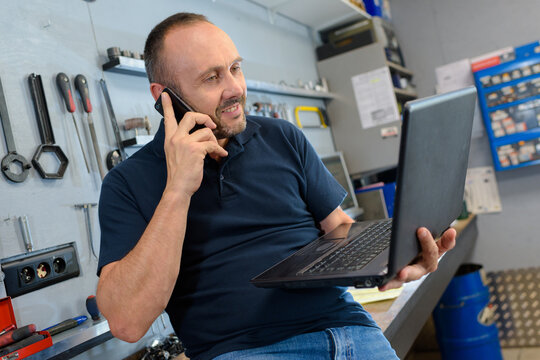 mid section of mechanic using laptop in workshop