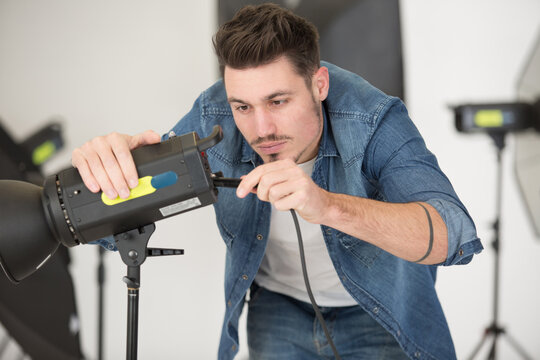 handsome male photographer fixing lights
