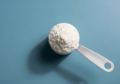 Measuring cup of flour on blue background for baking and cooking concepts