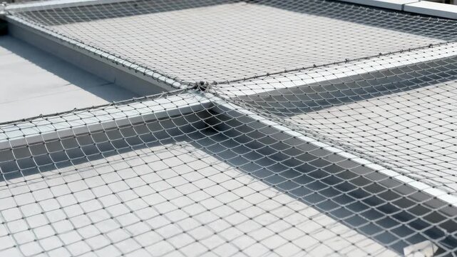 Medium shot capturing bird netting stretched over rooftop areas creating a safe barrier to keep birds away from sensitive zones.
