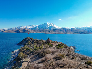 Spectacular aerial photograph of Akdamar Island and the Holy Cross Cathedral on Lake Van, Turkey. The historic church stands out against the deep blue lake and the majestic, snow-capped Süphan Mountai © Turkey Photo
