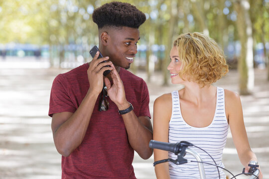 multiracial young couple with bicycle standing in park