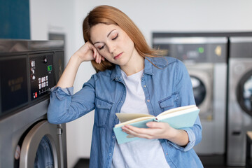 shot of a young woman reading a book in laundromat