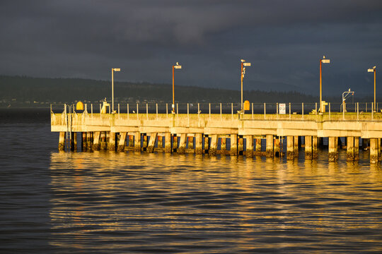 Concrete pier reflecting in calm sea water in warm evening glowing light - Powered by Adobe