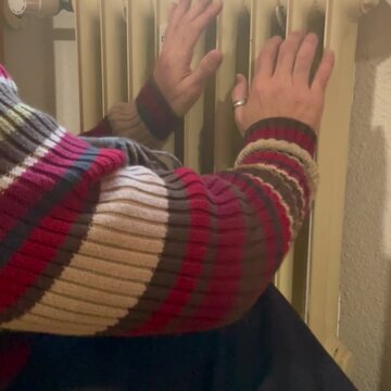 Calentando manos en el radiador calefactor del hogar