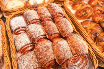 Freshly baked pastries arranged in woven baskets, showcasing a variety of sweet rolls and cinnamon twists, inviting indulgence and warmth in a cozy bakery setting