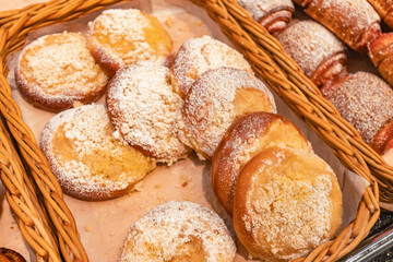 Freshly baked pastries with powdered sugar are arranged in a woven basket, showcasing a delightful assortment of sweet treats perfect for breakfast or dessert enjoyment