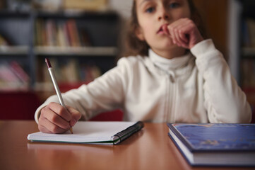 Child Writing in Library During Quiet Study Hour With Books Nearby