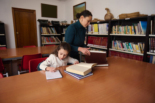 Mother and Daughter Studying Together in a Public Library, Exploring Books, Learning, and Knowledge
