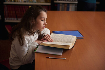Young Girl Reading a Book in Public Library During Study Time