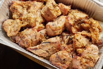 Close-up of grilled shashlik kebab pieces in a foil tray