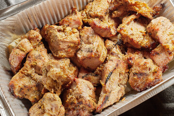 Close-up of grilled shashlik kebab pieces in a foil tray