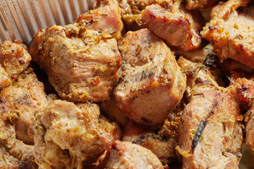 Close-up of grilled shashlik kebab pieces in a foil tray