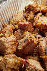 Close-up of grilled shashlik kebab pieces in a foil tray