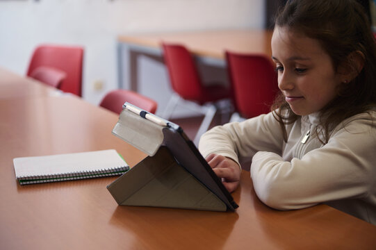 Girl Studying With Tablet In School Library During Book Day Activity