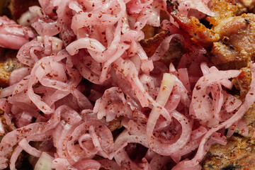 Close-up of grilled shashlik kebab pieces with marinated onions in a foil tray