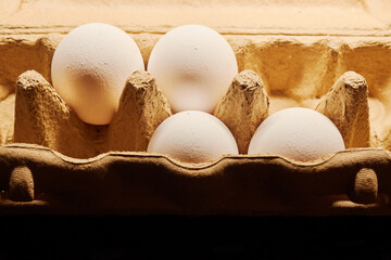 Close-up of several chicken eggs in a paper egg carton