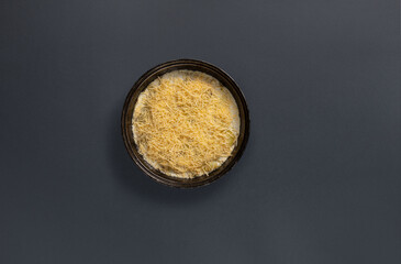 A hearty layered dish garnished with a generous amount of shredded cheese sits on a dark plate. This meal is perfect for a family gathering or special occasion.