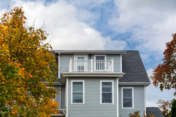 Charming suburban house framed by vibrant autumn trees and soft clouds in the Brighton area of Boston, Massachusetts, USA
