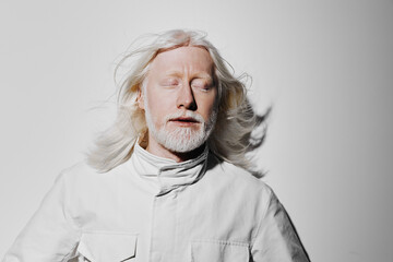 Portrait of a serene elderly man with long white hair and beard, wearing a white coat against a...