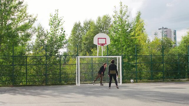 Playing soccer on the basketball court at a Moscow park on an overcast afternoon