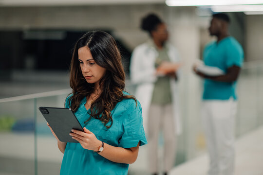Female medical professional using digital tablet with team - Powered by Adobe