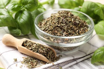 Dry basil leaves, fresh ones, bowl and scoop on napkin, closeup