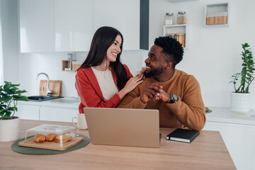 Interracial couple happy working remotely in kitchen