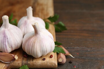 Fresh garlic, peppercorns and parsley on wooden table, closeup. Space for text