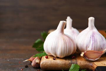 Fresh garlic, peppercorns and parsley on wooden table, closeup. Space for text