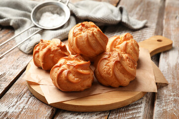 Fresh tasty profiteroles on wooden table, closeup