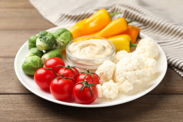 Different fresh vegetables and sauce on wooden table, closeup