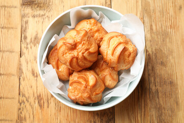 Delicious profiteroles on wooden table, top view