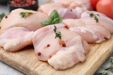 Raw chicken thighs with herbs and peppercorns on light table, closeup