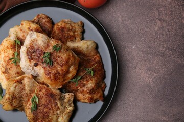 Tasty cooked chicken thighs with thyme on brown table, top view. Space for text