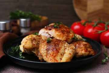 Tasty cooked chicken thighs with thyme and tomatoes on brown table, closeup