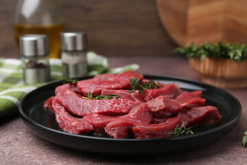 Pieces of raw beef meat and spices on brown table, closeup