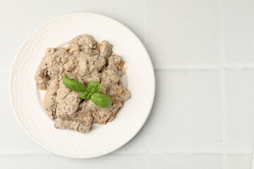 Tasty beef Stroganoff with basil on white tiled table, top view. Space for text